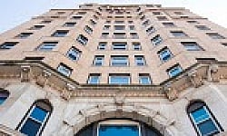 Impressive architectural facade of an elegant urban apartment building with classic design elements and large windows.