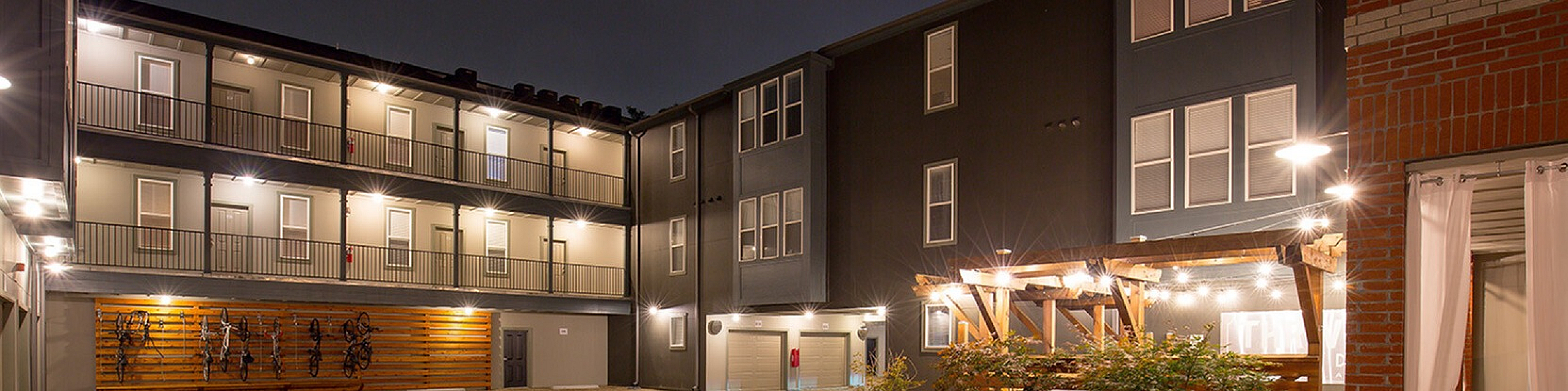 Chic urban apartment complex with warm night lighting, featuring a stylish courtyard and modern architecture.