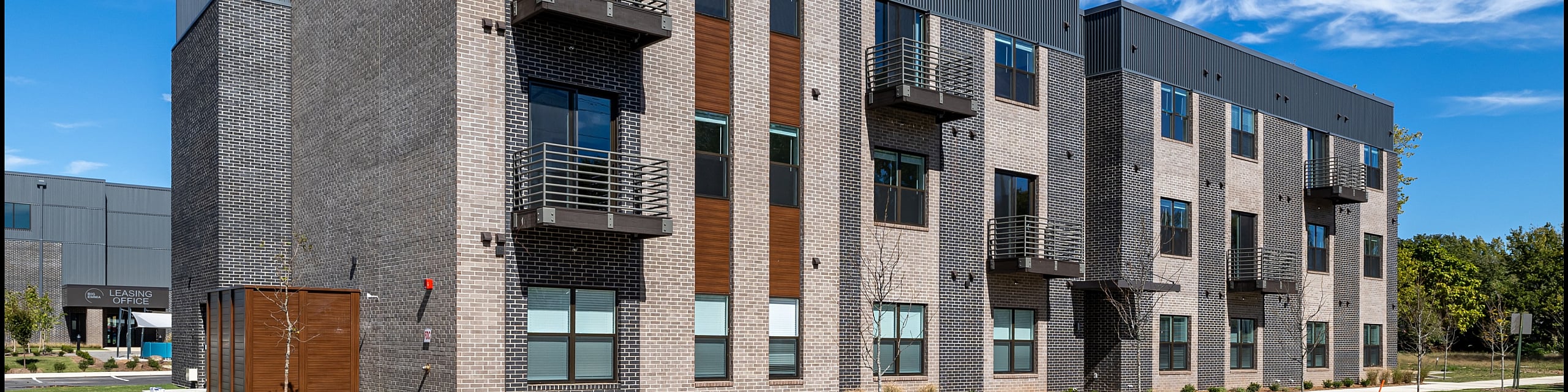 Modern three-story apartment building with stylish balconies and sleek brick facade in a vibrant neighborhood.