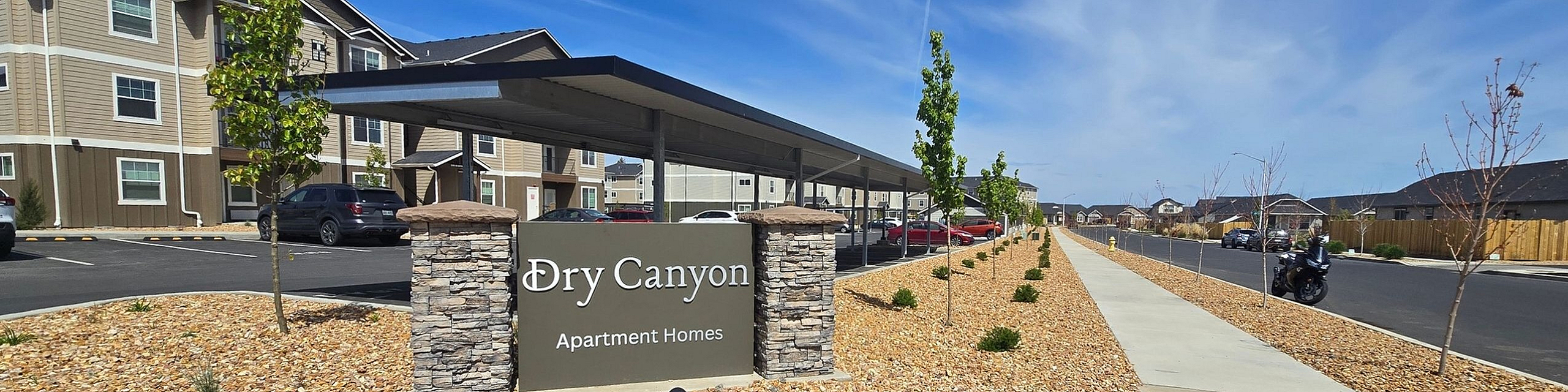 Inviting exterior view of Dry Canyon Apartment Homes showcasing modern architecture and beautifully landscaped surroundings with ample parking.
