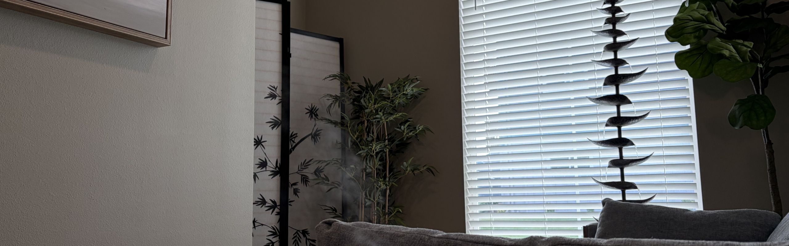 Elegant living space with natural light filtering through blinds, featuring lush potted plants and stylish decor.