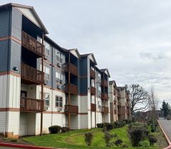 Modern apartment complex with charming balconies, surrounded by lush greenery and a well-maintained walkway.