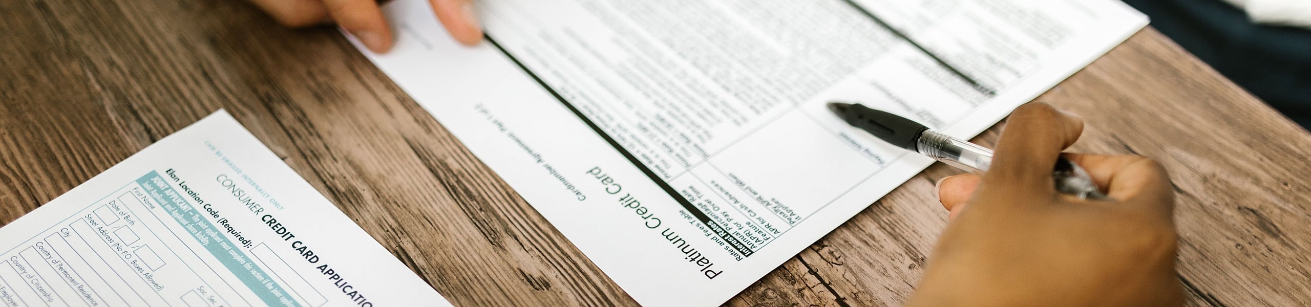Inviting scene with a close-up of a person reviewing documents on a wooden table, highlighting a focused and productive atmosphere.
