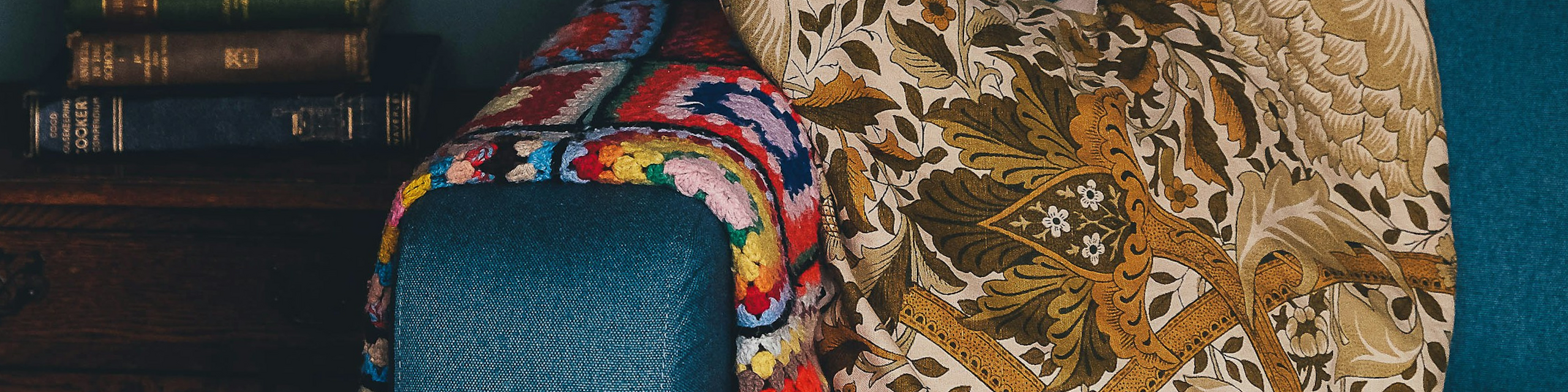 Cozy, stylish living room corner featuring a vibrant patchwork quilt and elegant floral tapestry, creating a warm and inviting atmosphere.