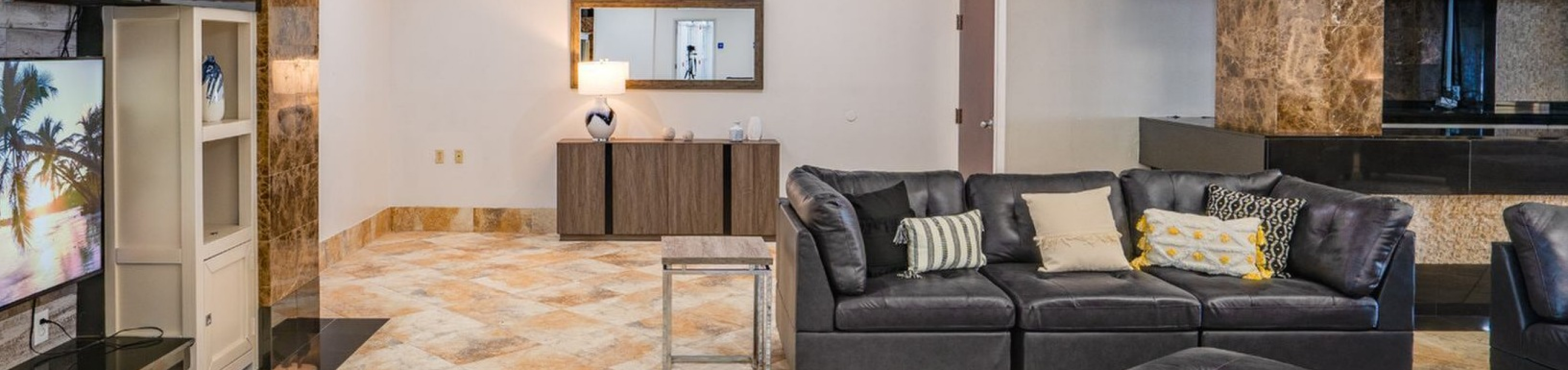 Elegant open-concept living space with luxurious leather seating, modern entertainment center, and stylish marble accents.