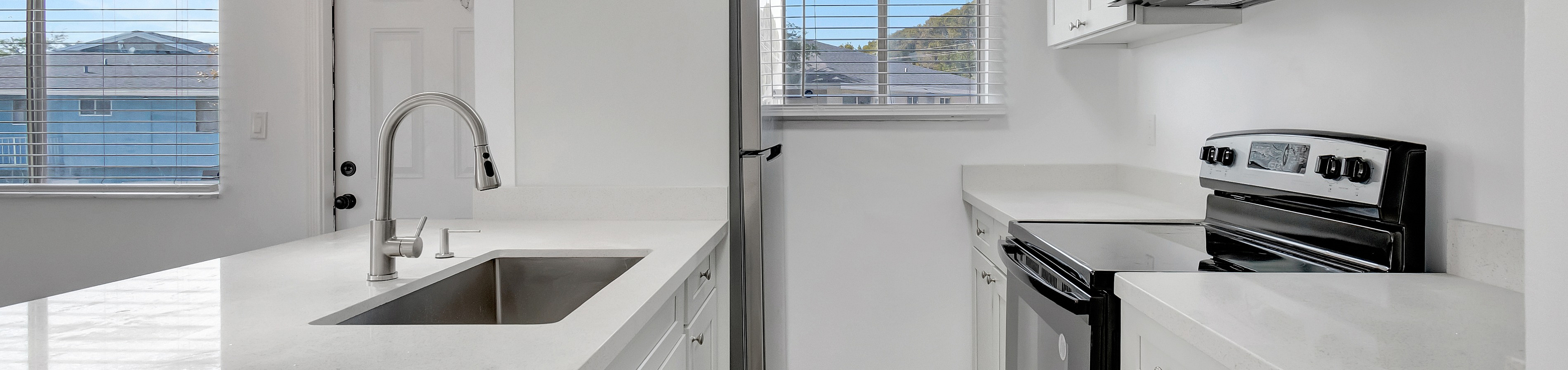 Bright, modern kitchen with sleek white cabinetry, stainless steel appliances, and elegant pendant lighting, perfect for culinary enthusiasts.
