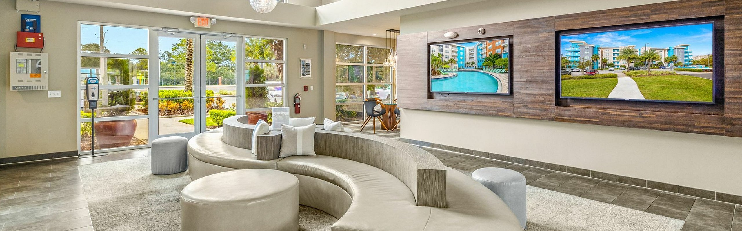 Modern and inviting apartment lobby featuring luxurious curved seating and vibrant artwork, enhanced by natural light from large windows and stylish pendant lighting.