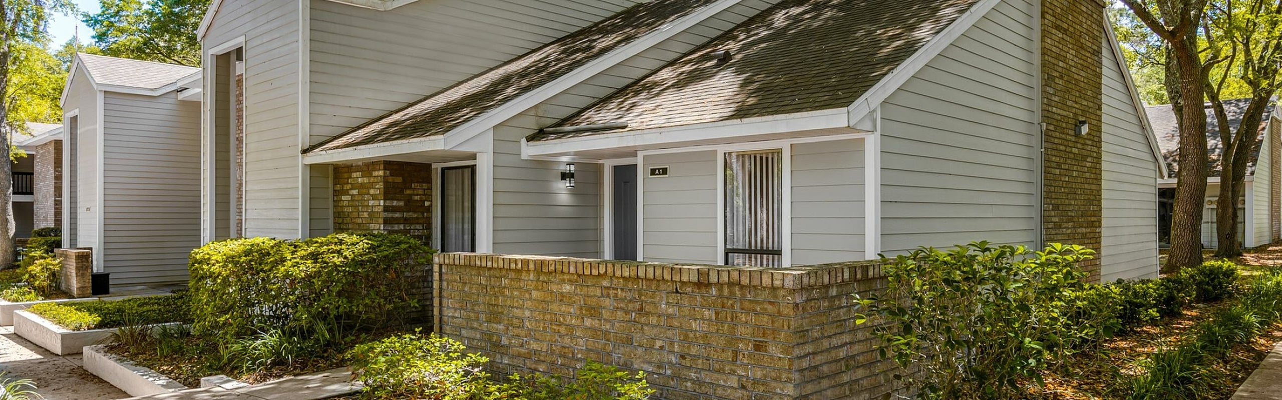 Charming townhouse with modern architecture, nestled among lush greenery, featuring a cozy front porch and manicured walkway.