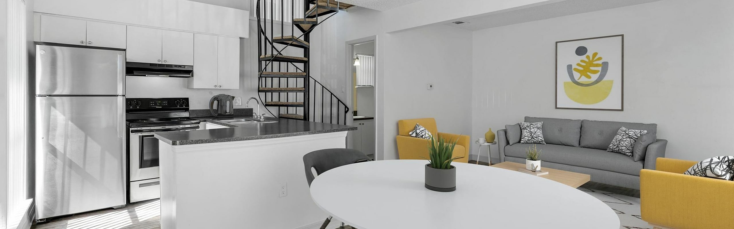 Modern open-concept loft apartment with sleek kitchen, spiral staircase, and bright living area with stylish decor.