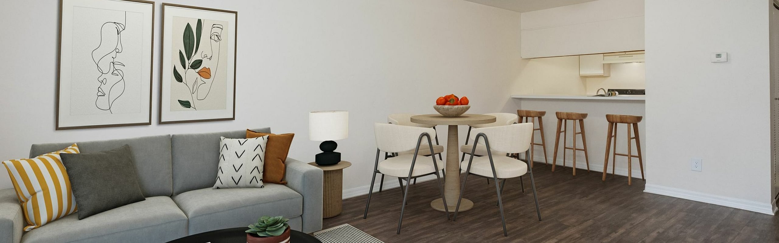Modern living space with a cozy gray sofa and vibrant pillows, stylish artwork, elegant dining area, and open kitchen with bar stools.