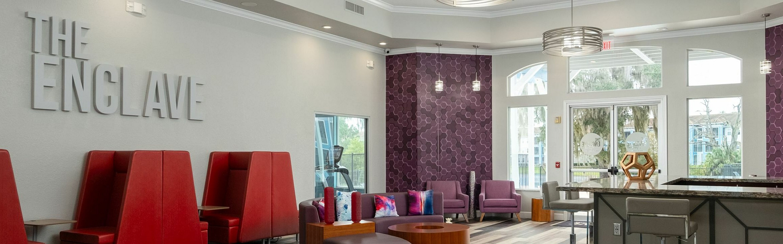 Modern communal lounge with vibrant red seating, stylish geometric decor, and an inviting ambience at The Enclave apartments.