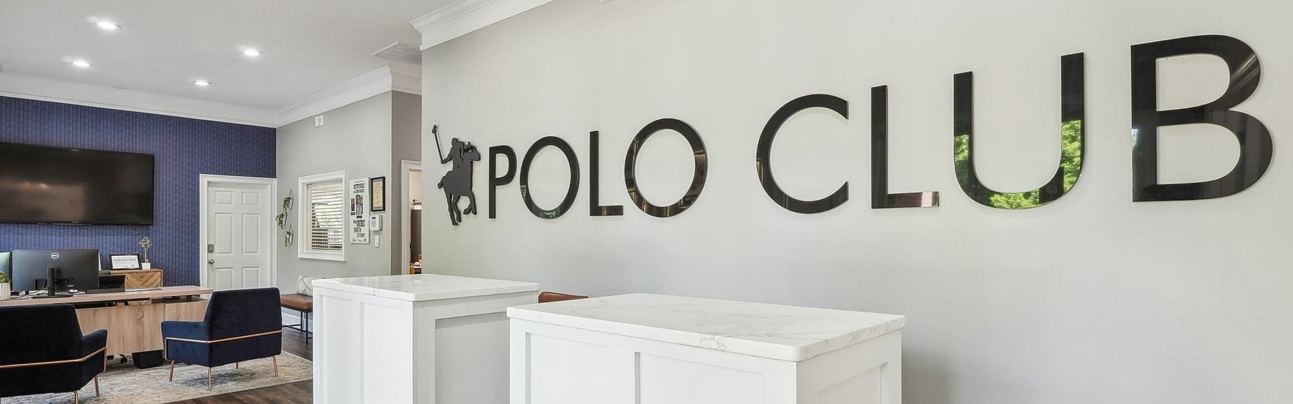 Modern office interior with stylish reception desk and Polo Club logo, featuring sleek hardwood floors and contemporary design.