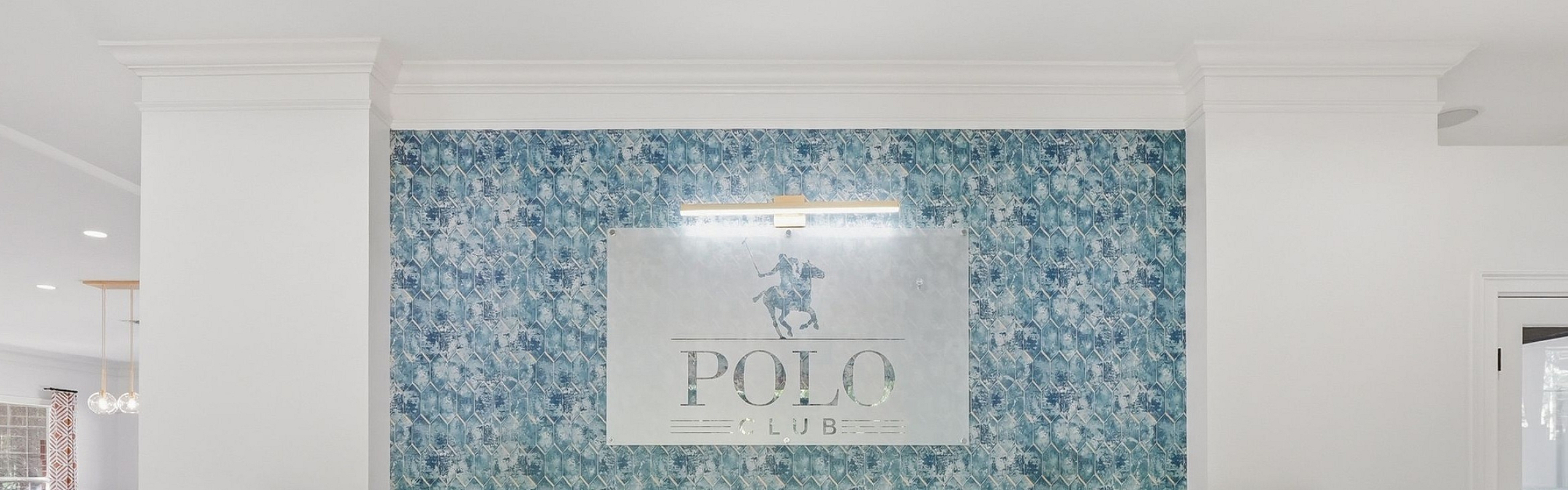 Welcome to the Polo Club's elegant lobby featuring sophisticated white desks and a textured blue accent wall, creating a chic and inviting atmosphere.