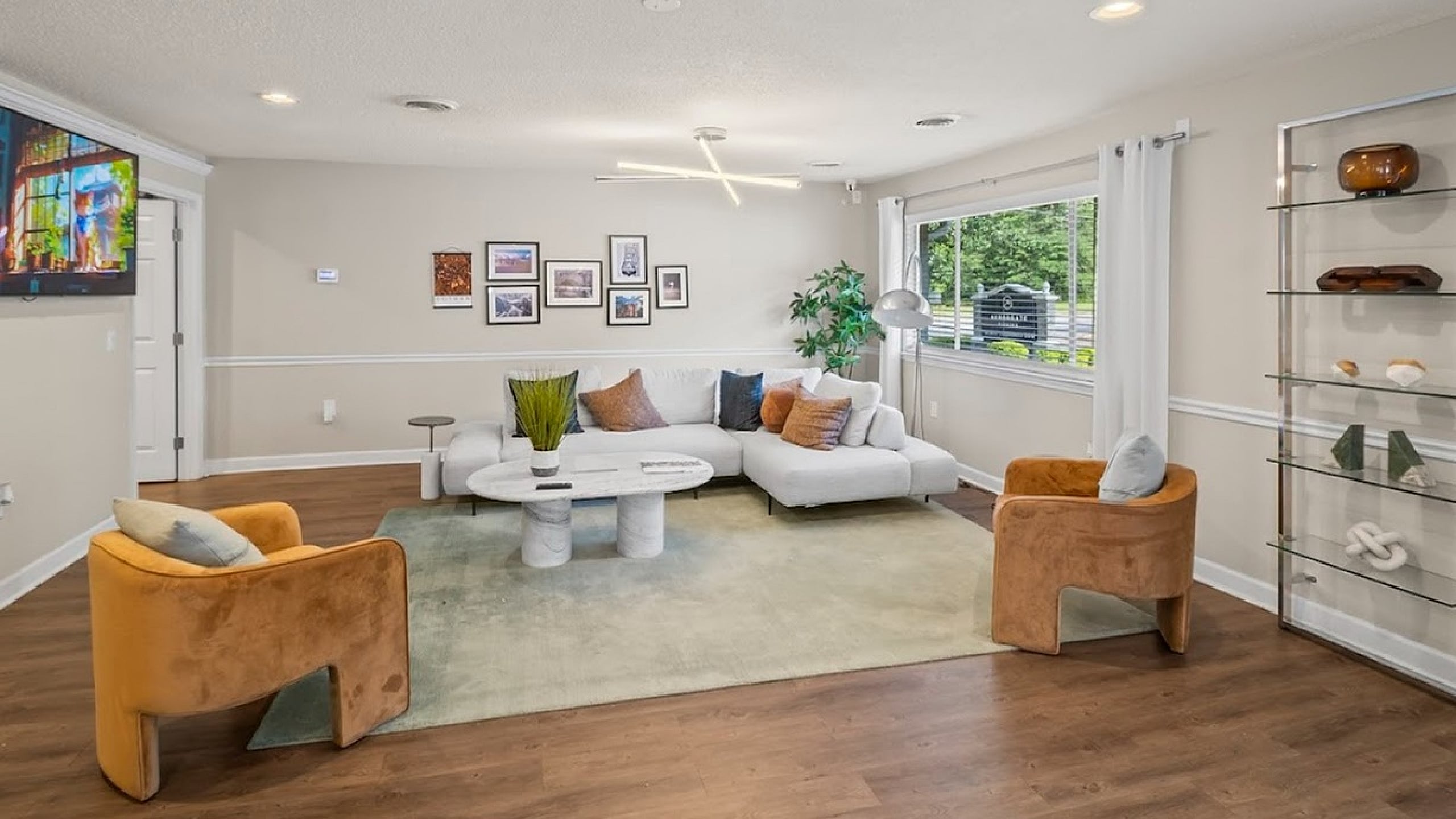 Inviting living room with white sectional sofa, modern decor, large window, and warm wooden floor.