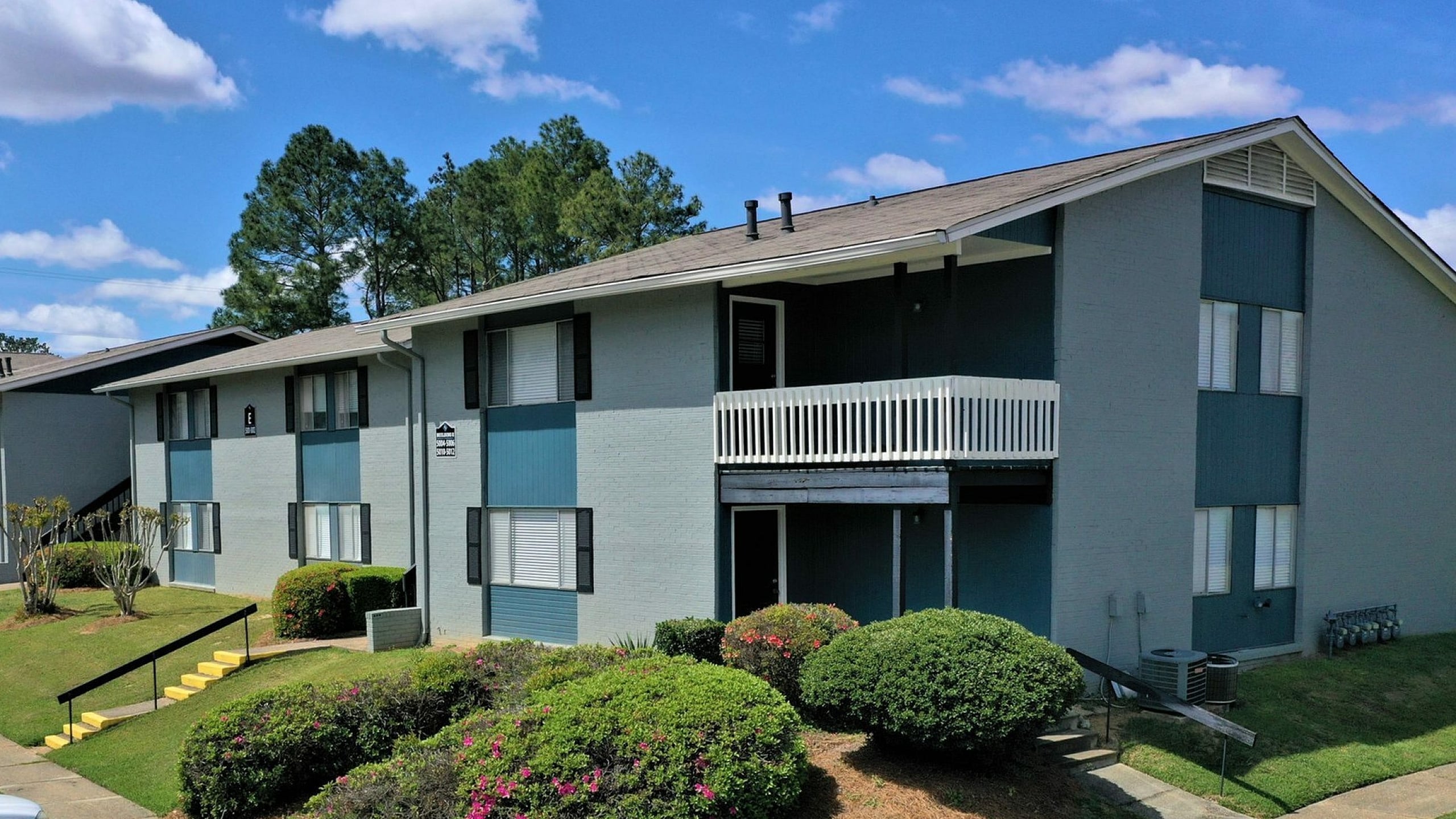 Inviting apartment complex with well-maintained landscaping and ample parking space.