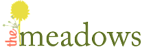 Elegant logo for 'The Meadows' featuring a vibrant yellow flower symbolizing growth and freshness.