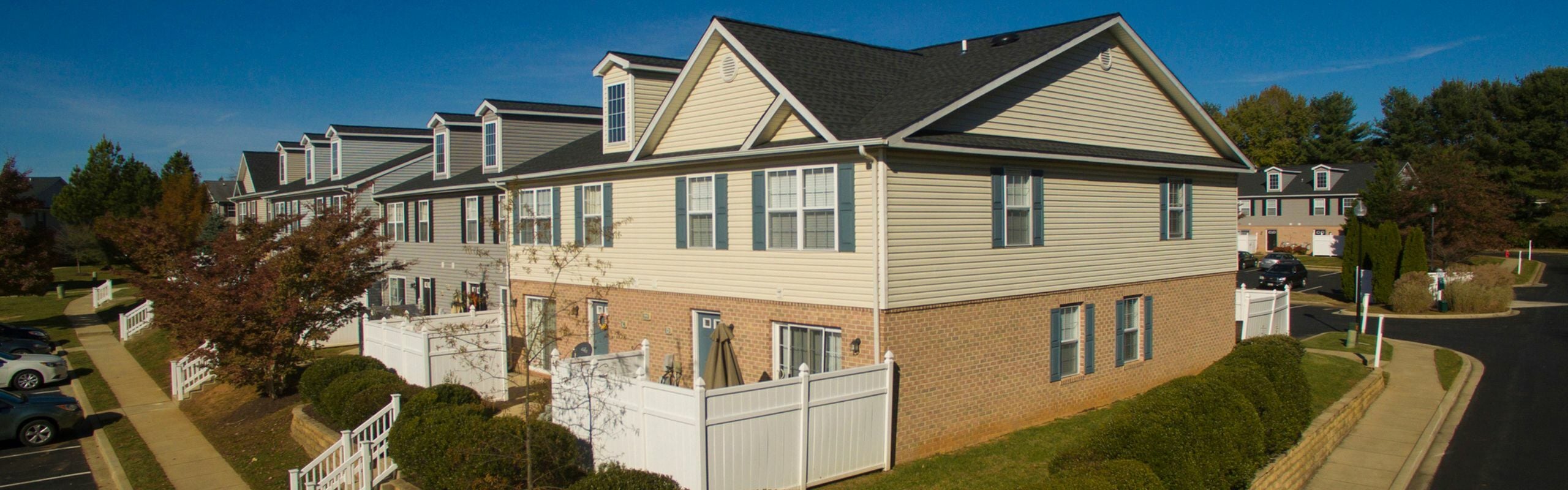 Charming suburban townhouse with modern siding and lush landscaping, nestled in a peaceful neighborhood street.