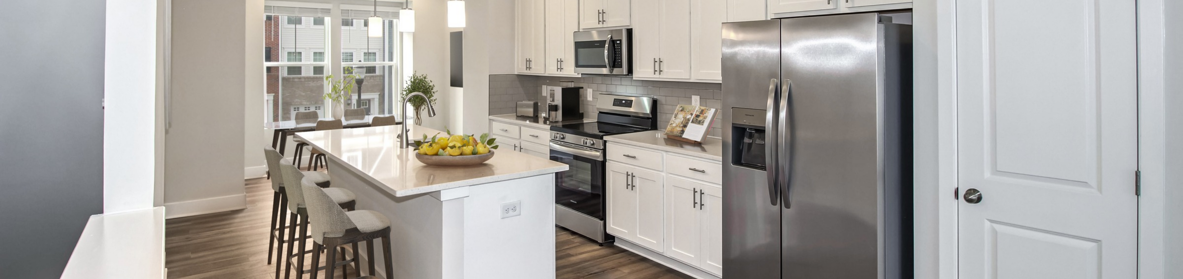 Panoramic view of modern kitchen with stainless appliances and stone countertops with Shaker cabinets at the newly built Terrace at Sycamore Ridge Townhomes in Frederick, MD.