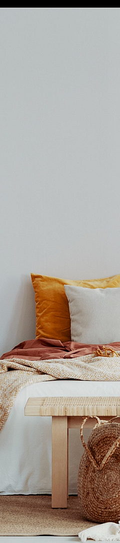 Chic bedroom interior showcasing a cozy bed with colorful cushions, natural wood accents, and stylish decor elements.