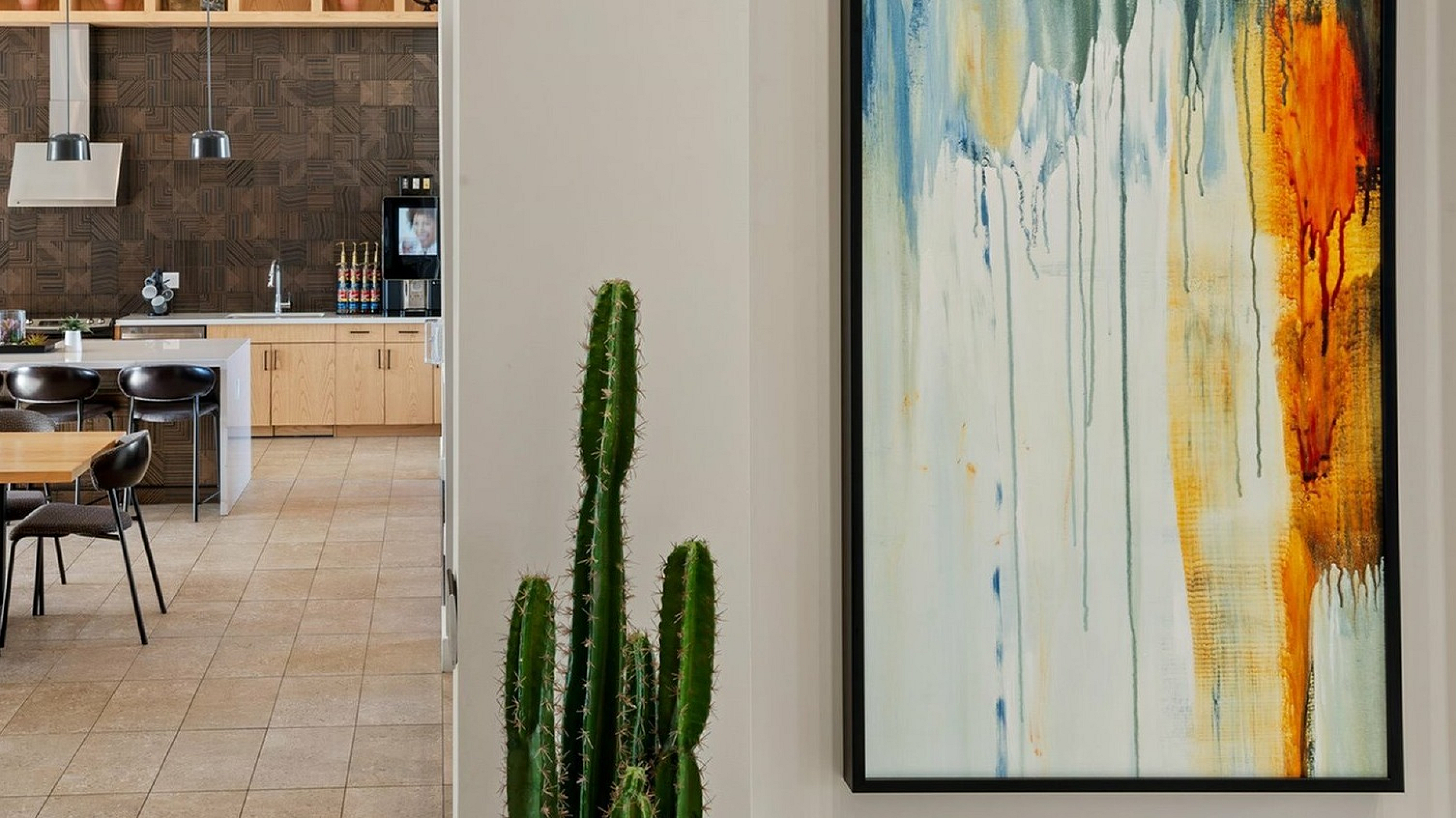 Chic open-concept kitchen featuring elegant pendant lighting, modern cabinetry, and vibrant abstract artwork, perfect for stylish living.