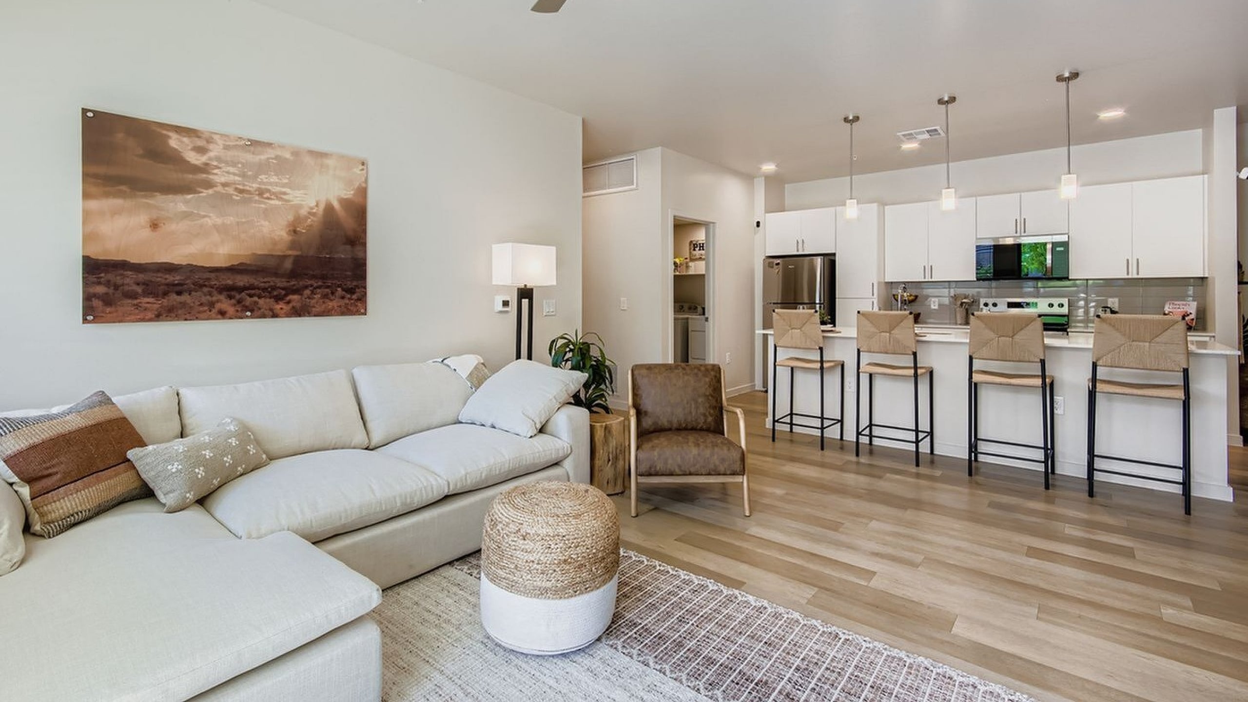 Modern open-concept living room with cozy beige sectional, stylish kitchen island, and sleek stainless steel appliances.