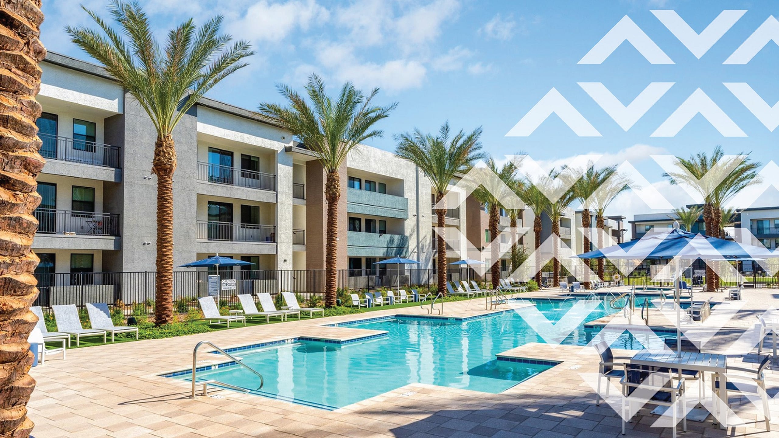 Modern apartment complex with a sunny poolside area, palm trees, and lounging chairs, offering a luxurious and relaxing environment.