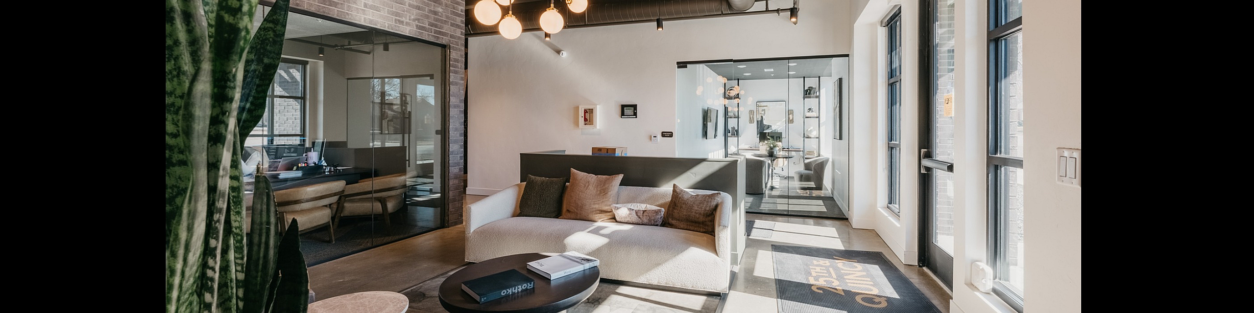 Modern and inviting apartment lobby with stylish seating area, chic chandelier, large windows, and natural light.