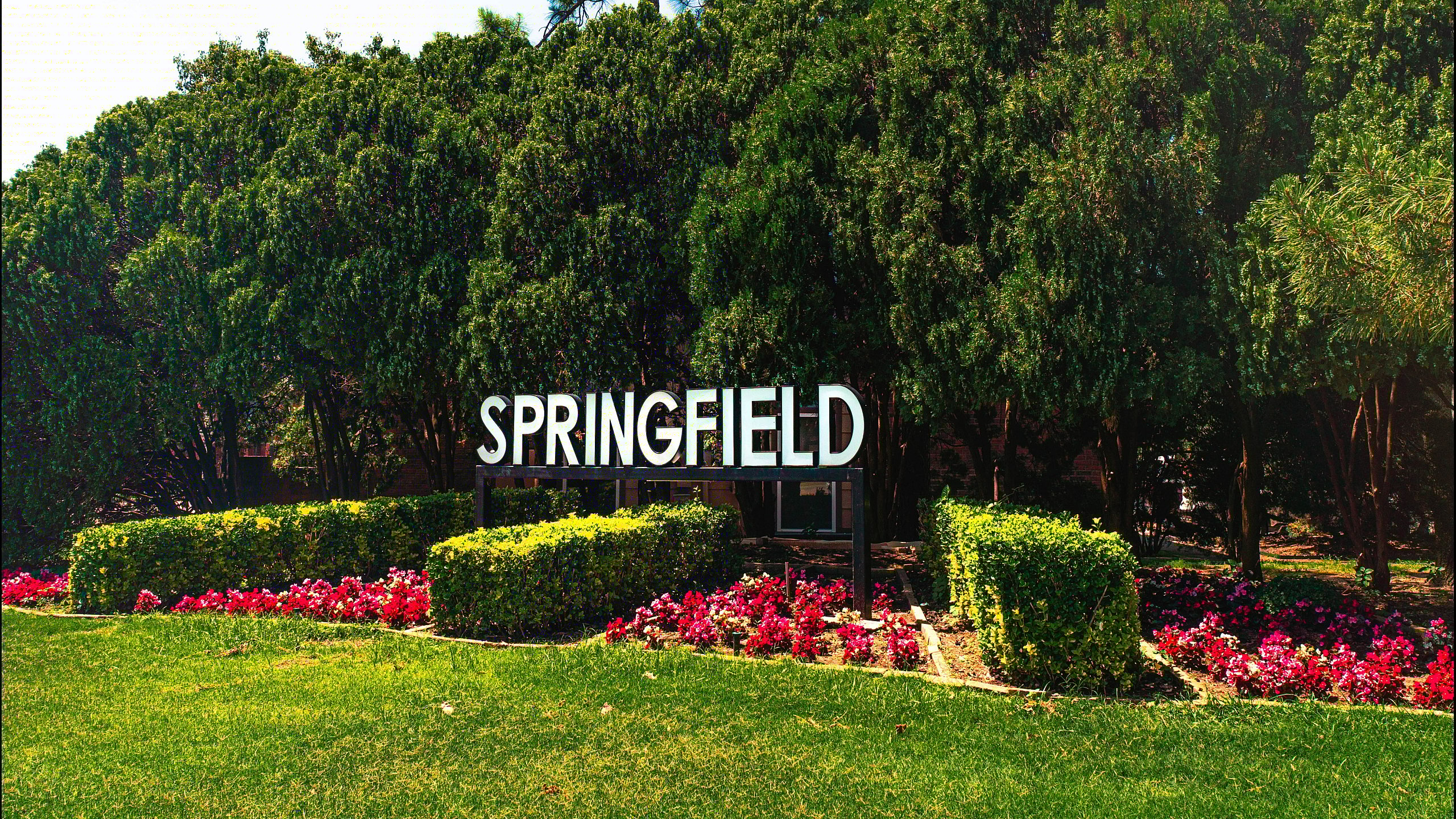 Lush entrance to Springfield Gardens community with vibrant greenery and flowers.