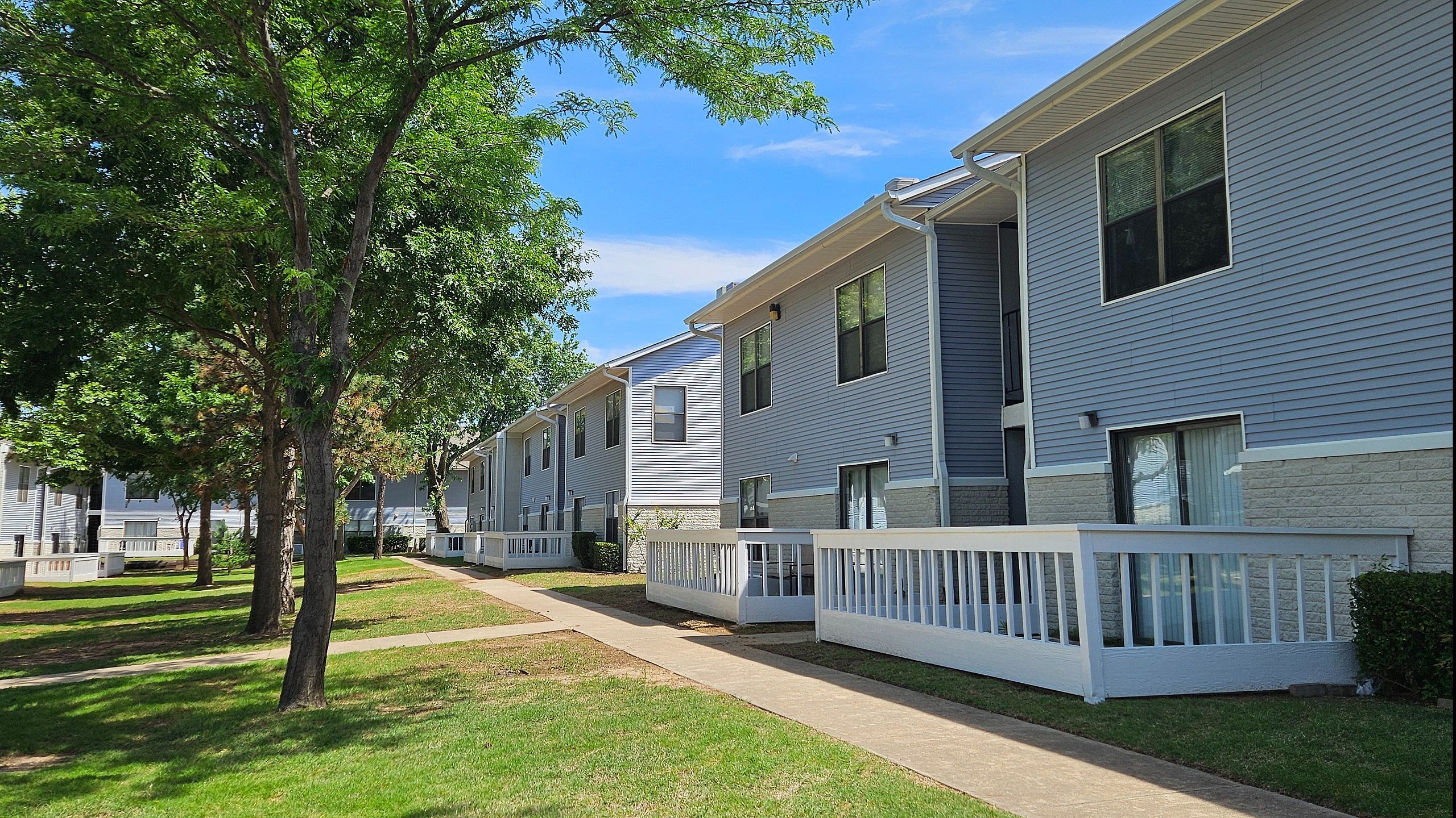 Charming apartment buildings surrounded by lush greenery and a spacious lawn.