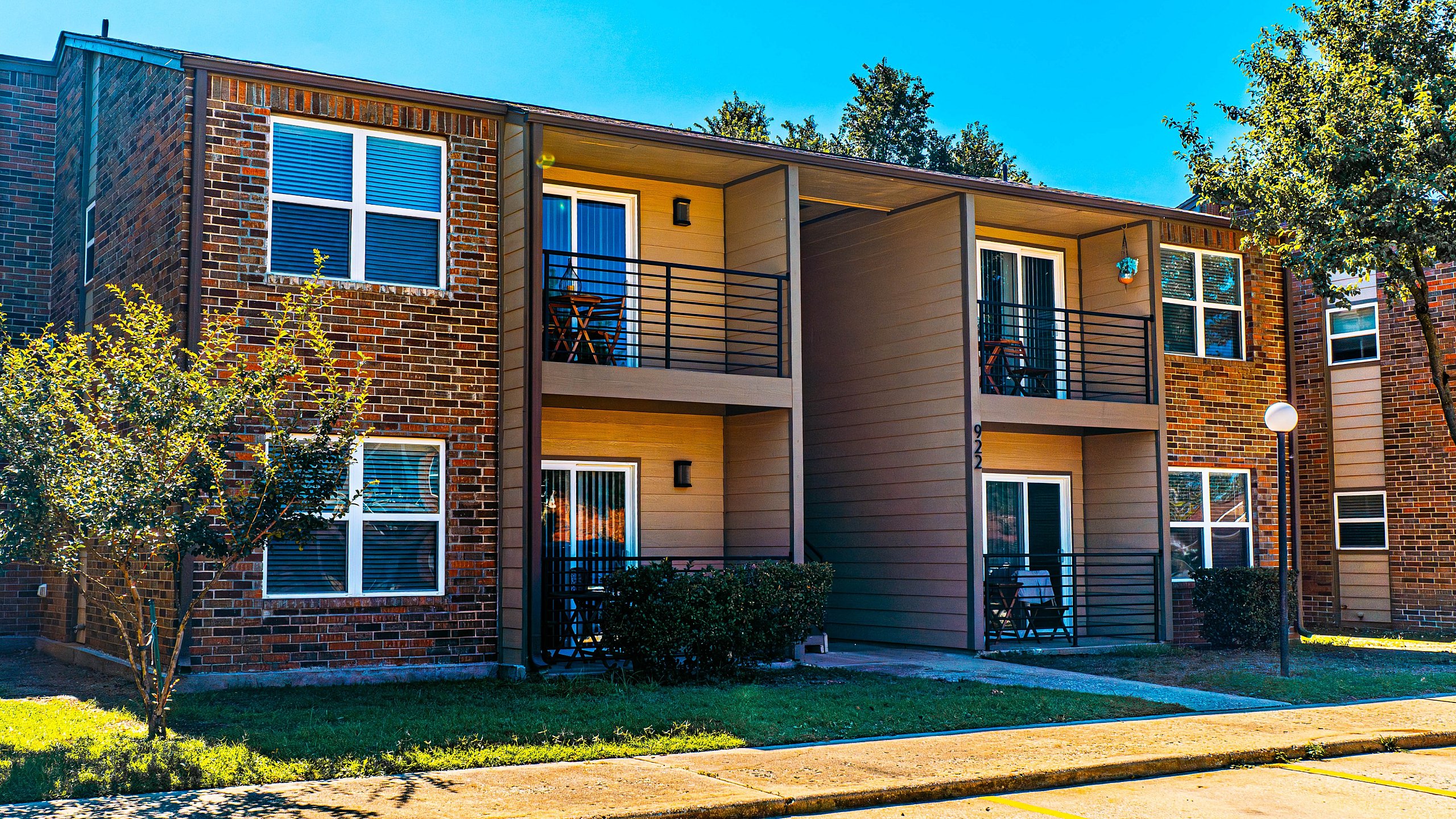 Inviting two-story apartment building with private balconies and landscaped surroundings.