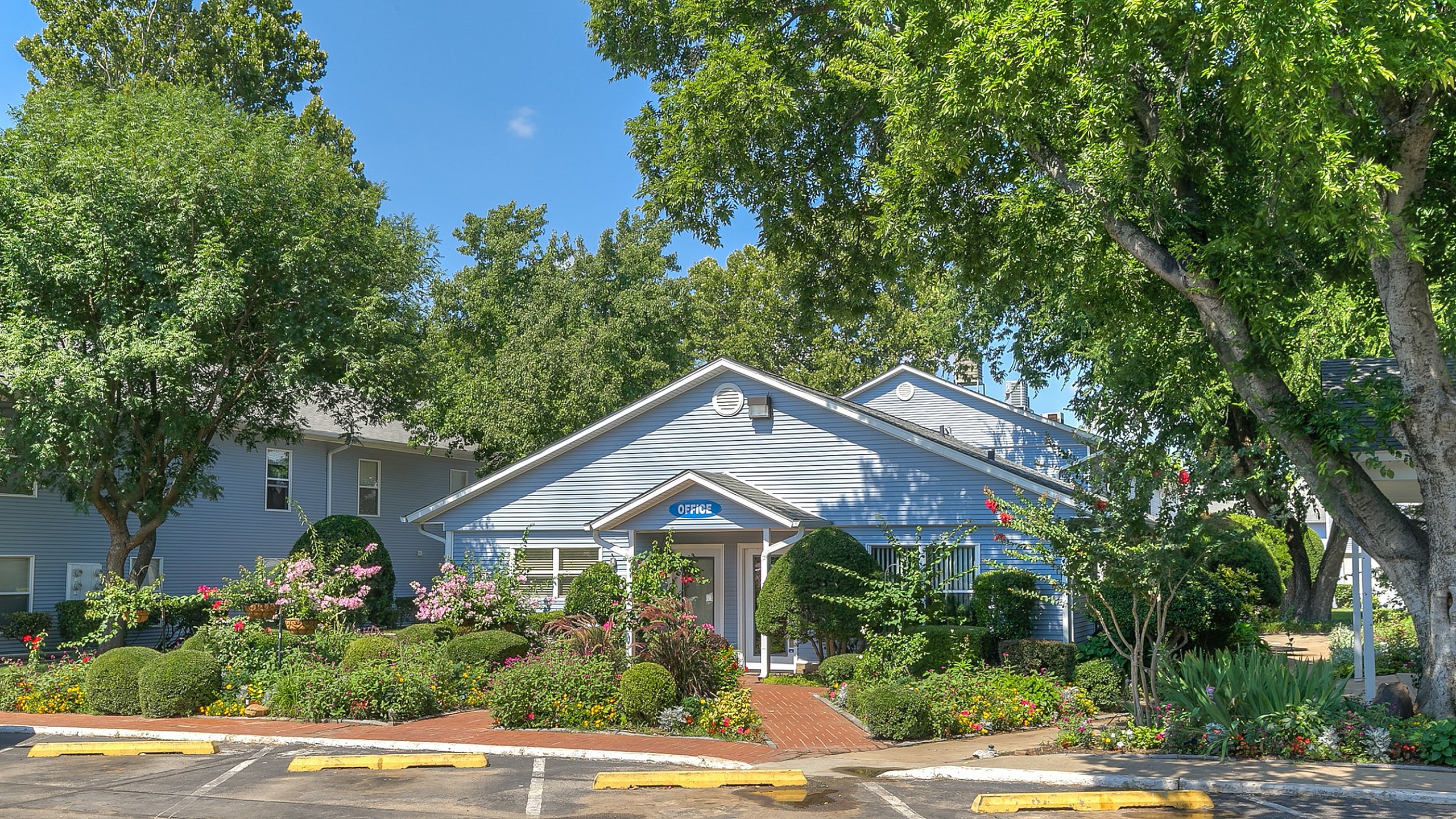Inviting community entrance with lush greenery and vibrant flowers.