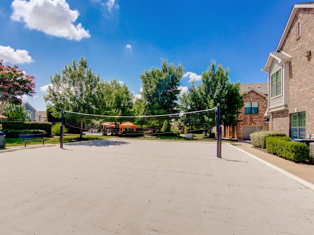 View of Sand Volleyball Court, Showing Net, Benches, and Building Exteriors at Enclave on Golden Triangle Apartments