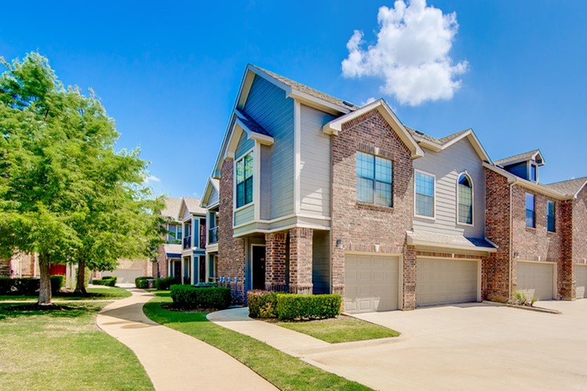 View of Building Exterior, Showing Landscaping and Private Attached Garages at Enclave on Golden Triangle Apartments