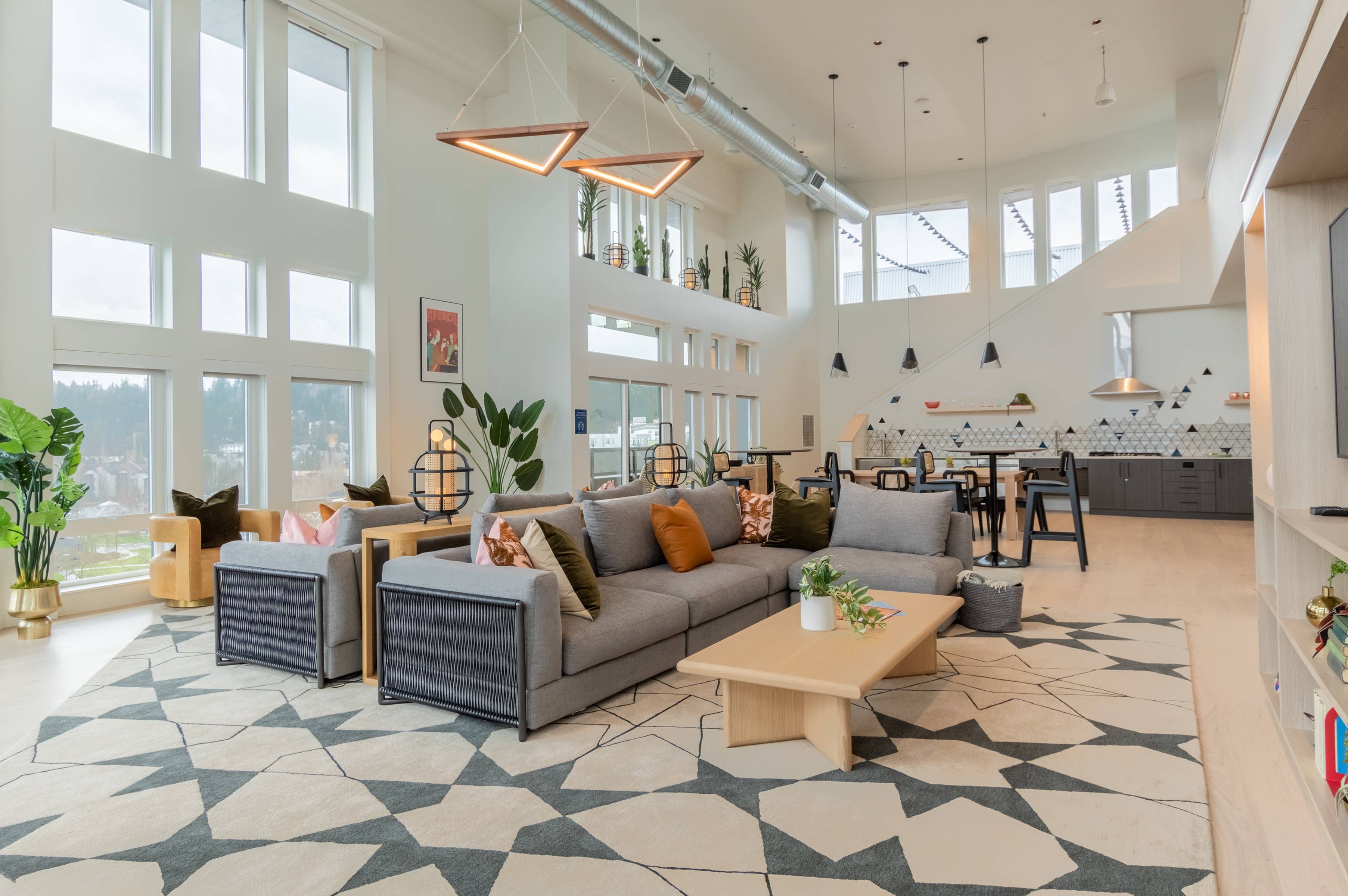 Alpine-inspired sky lounge with 2 large gray couches, dining areas and kitchen area