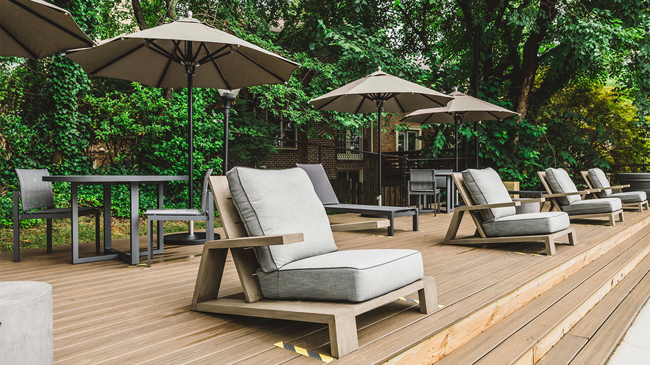 Sundeck in pool area with new patio chairs, umbrellas and tables