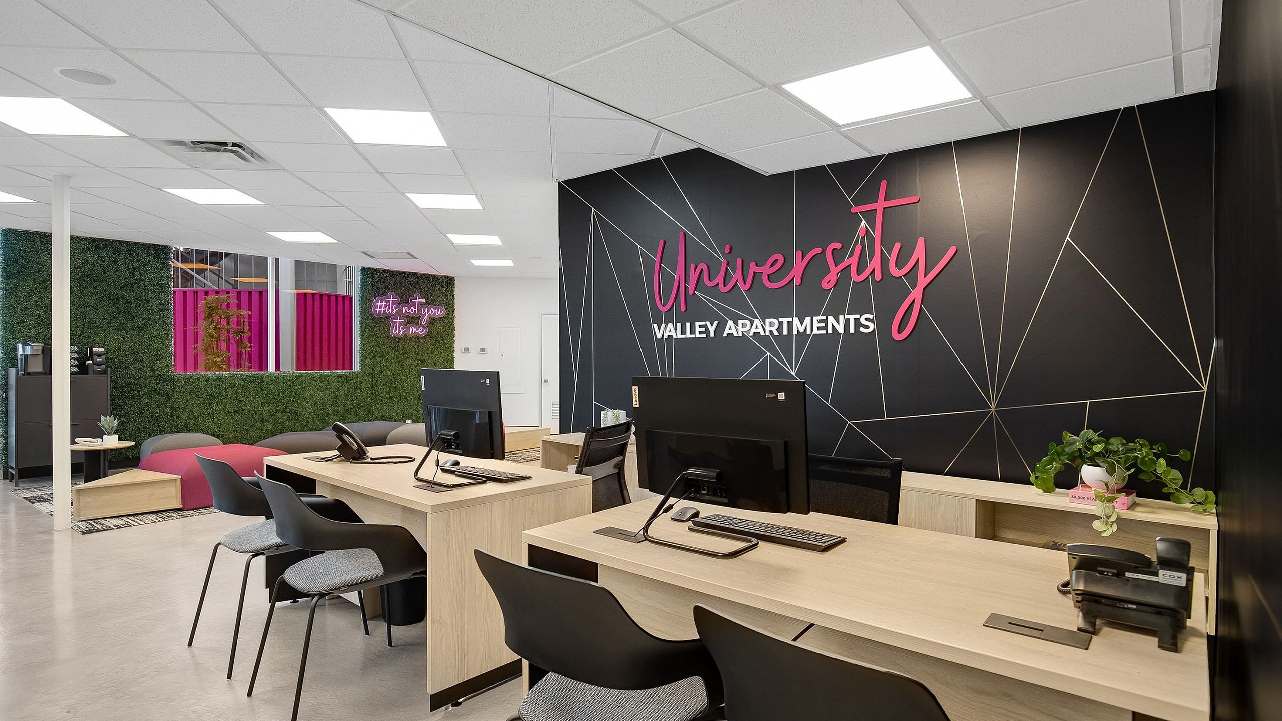 Modern and inviting leasing office for University Valley Apartments, featuring sleek workstations, vibrant greenery, and stylish lighting. A welcoming space for prospective residents.