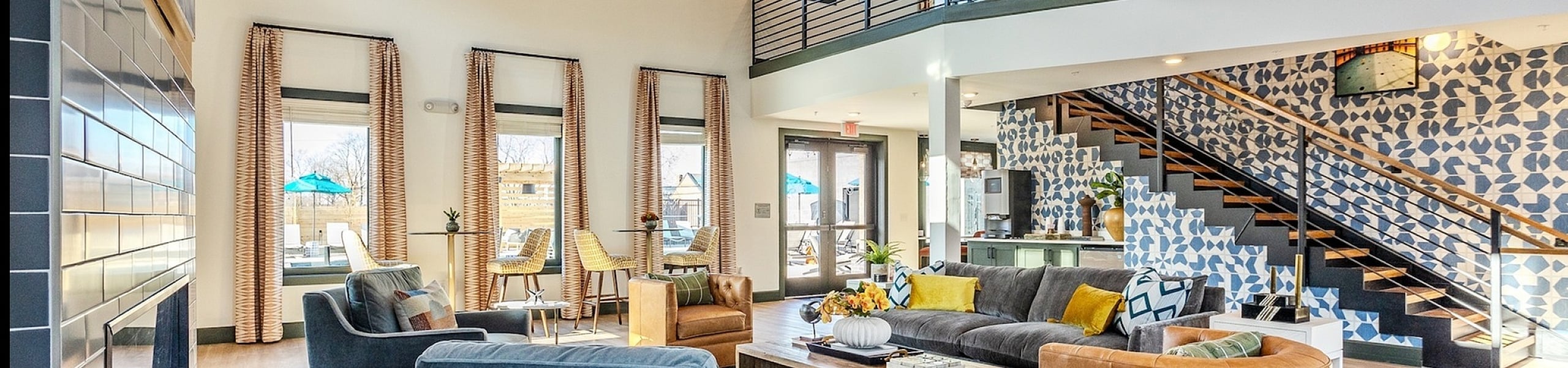 Luxurious modern lounge area featuring stylish seating, contemporary decor, and an elegant staircase in a vibrant open-plan space.