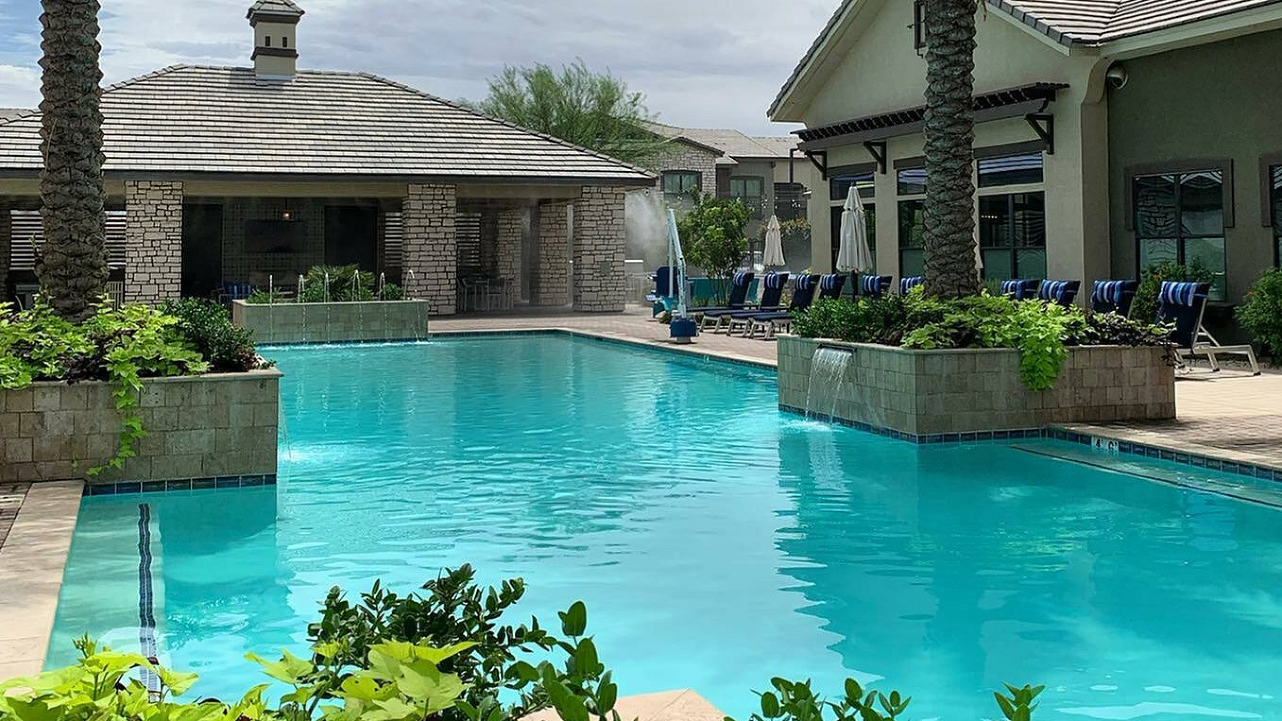 Luxurious apartment complex with inviting swimming pool, surrounded by lush greenery and palm trees, perfect for relaxation.