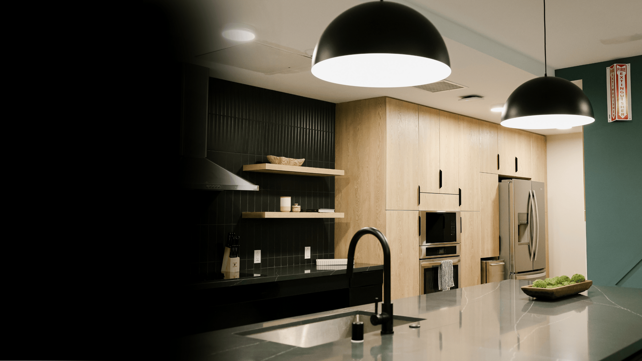 Modern kitchen featuring wood-paneled cabinetry, stainless-steel appliances, and a large quartz island with pendant lighting, highlighting a stylish amenity space ideal for contemporary apartment living.