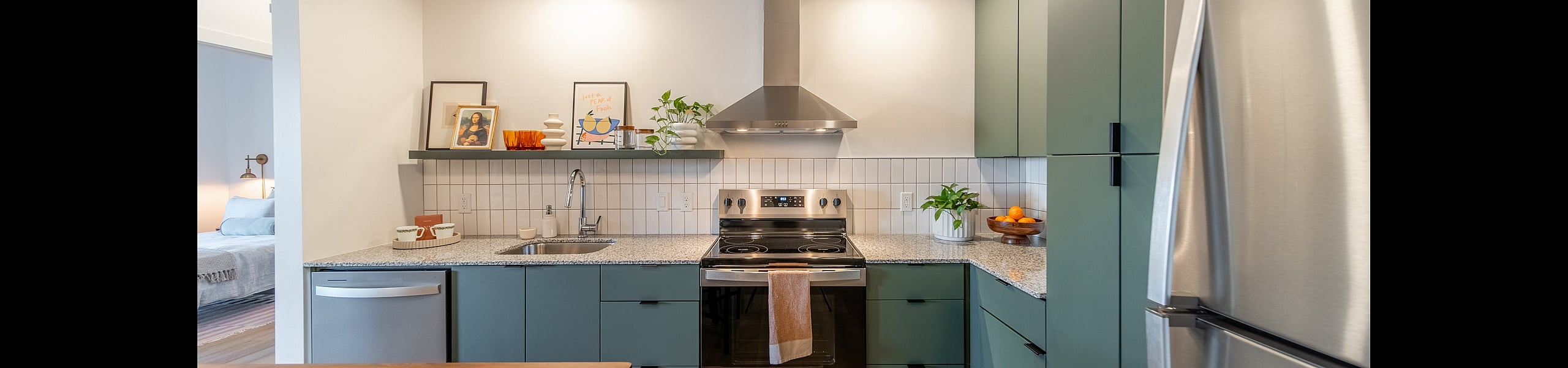 Chic modern kitchen with sleek stainless steel appliances, green cabinetry, and granite countertops, offering a stylish and functional cooking space.