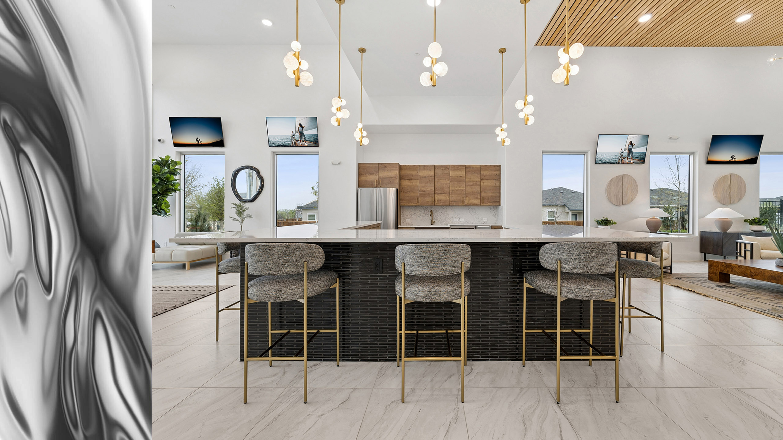 Modern kitchen with sleek pendant lights, elegant marble countertops, and stylish bar seating in a bright, open-layout living space.
