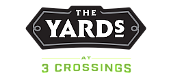 Logo of The Yards at 3 Crossings, featuring bold white lettering on a black geometric background with green accents.