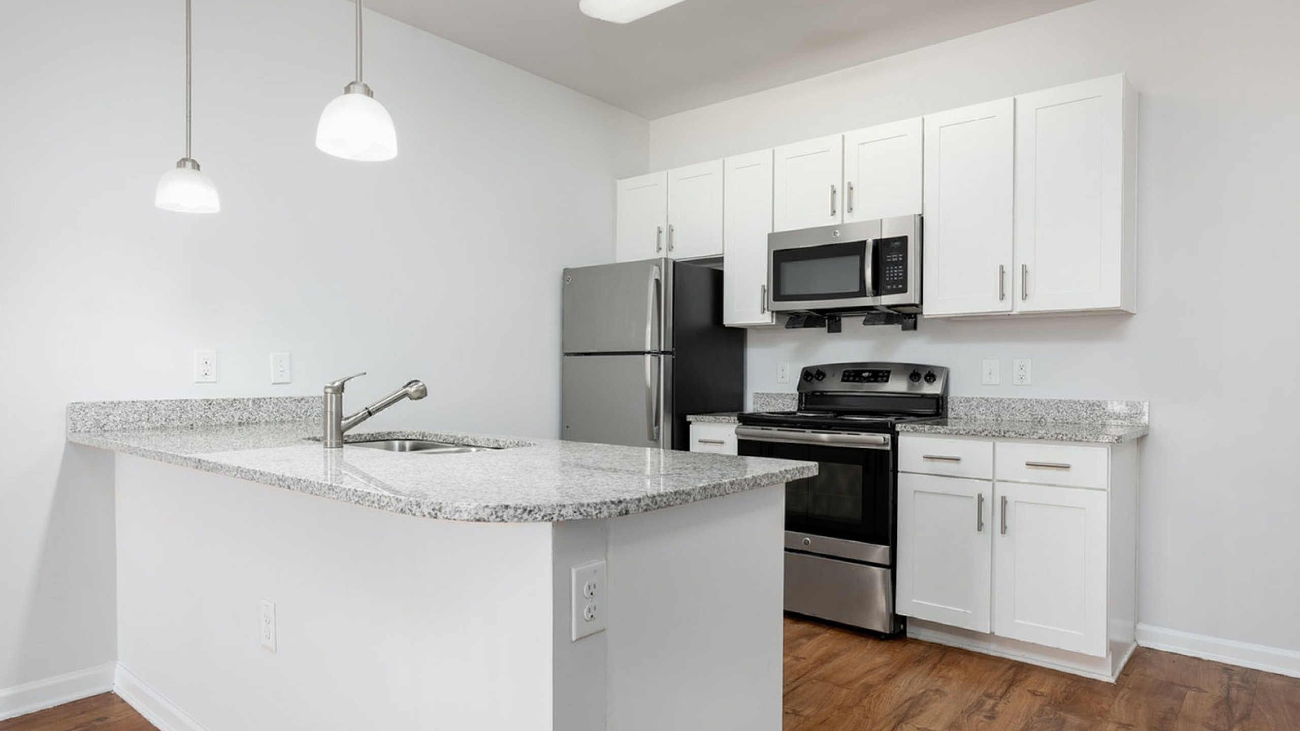 Modern kitchen with sleek granite countertops, stainless steel appliances, and elegant pendant lighting.