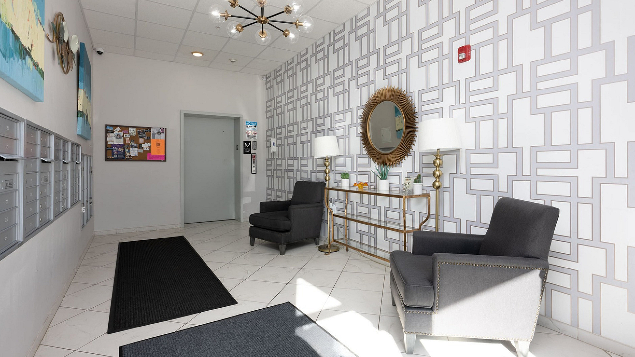 Elegant apartment lobby with modern decor, featuring stylish seating, geometric patterned wallpaper, and chic lighting.