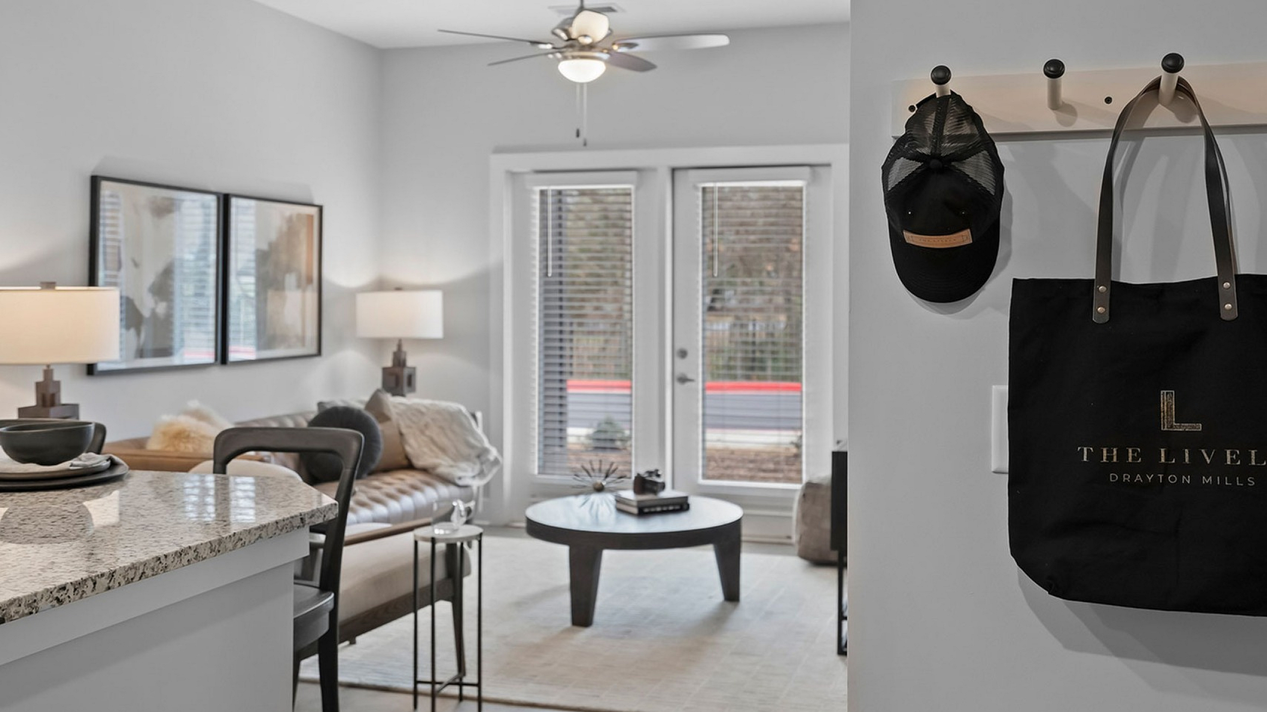 Modern apartment living room with elegant decor, featuring a cozy beige sofa, stylish artwork, and a granite breakfast bar under soft lighting.