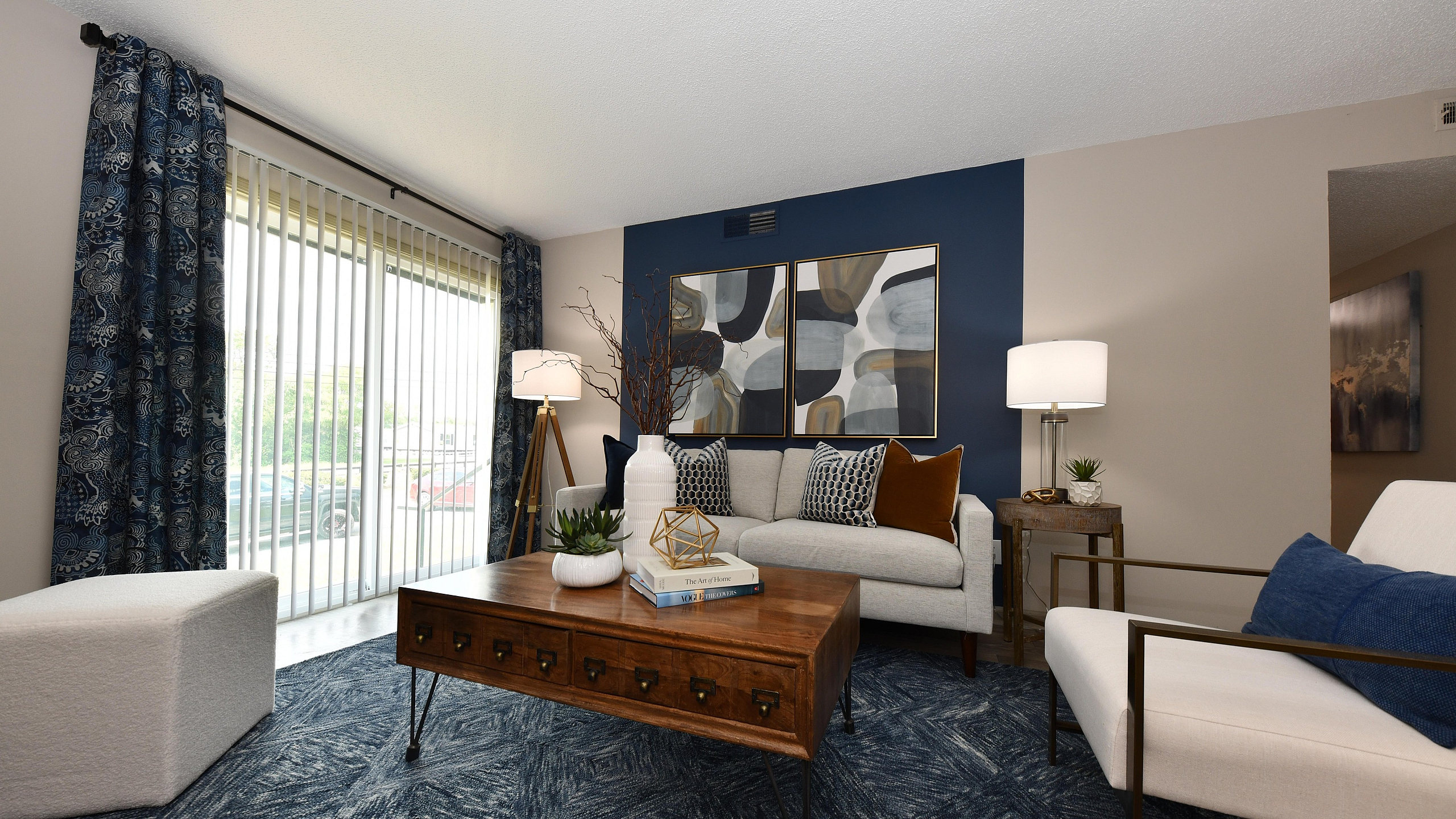 Chic living room with stylish decor, featuring a modern sofa, abstract artwork, and large windows with elegant drapes.