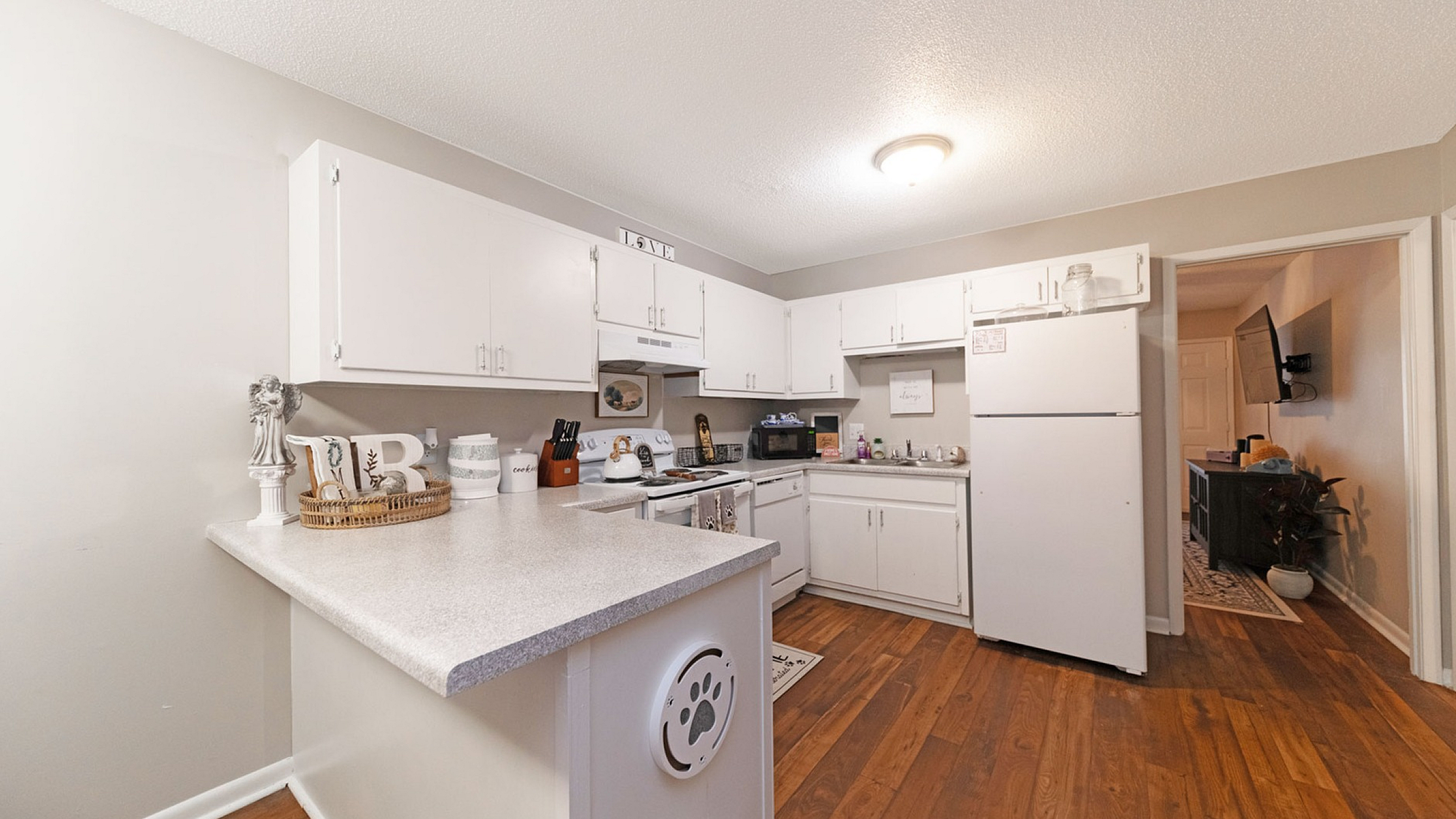 Charming modern kitchen with white cabinetry, sleek countertops, and warm wood flooring, perfect for culinary enthusiasts.