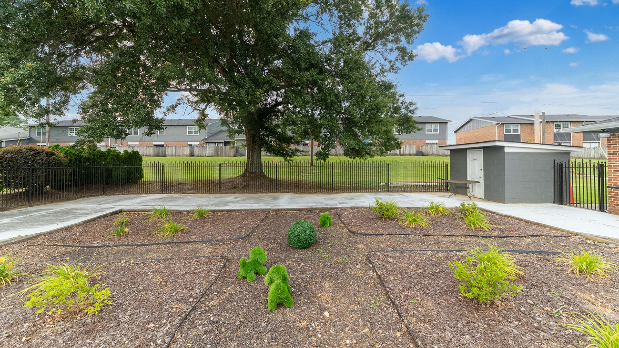 Charming outdoor space featuring a large tree, meticulously maintained garden, and vibrant green landscaping, ideal for relaxation and gatherings.