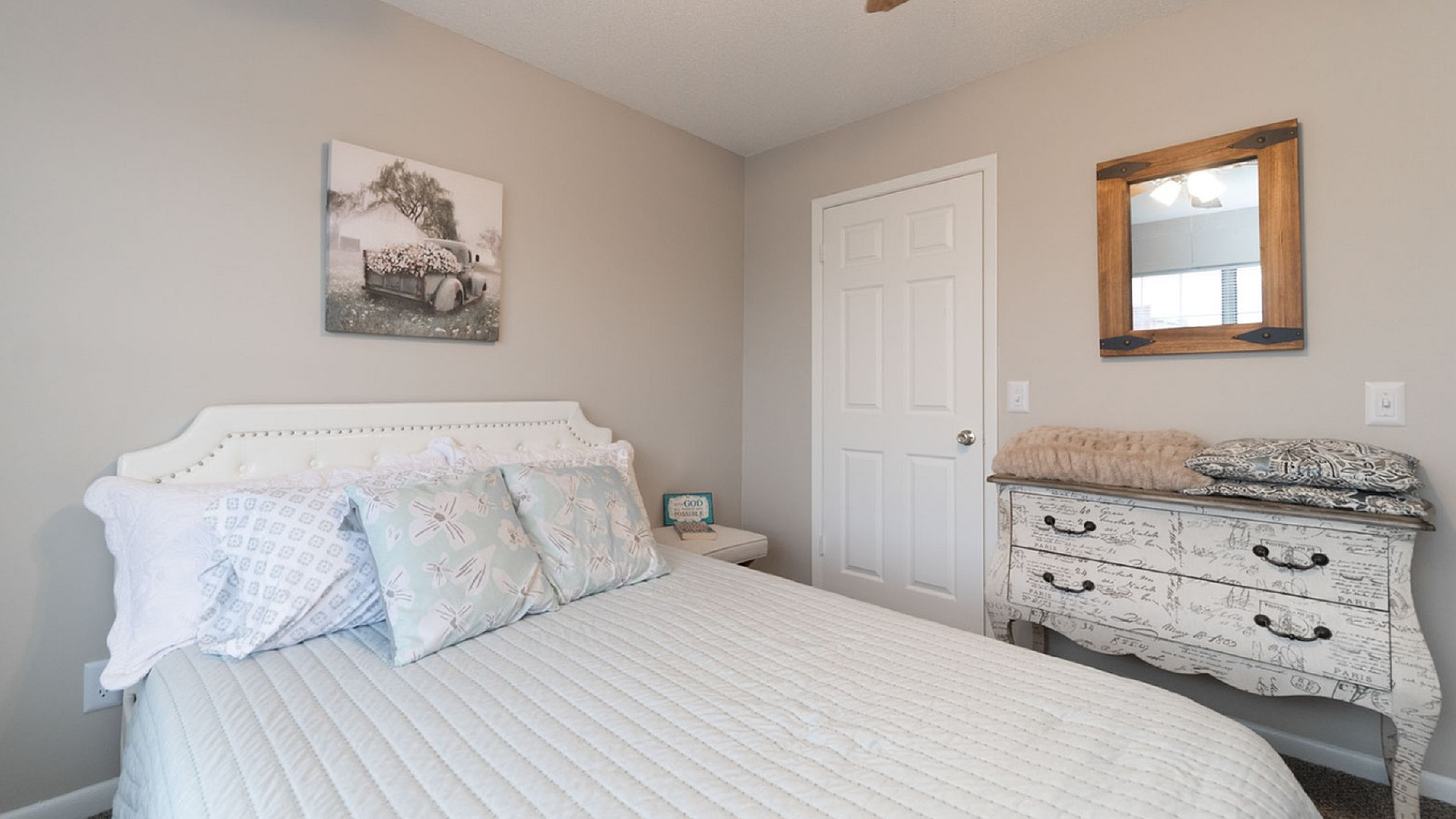 Charming bedroom with elegant decor, featuring a cozy bed, stylish throw pillows, and a vintage dresser under warm lighting.