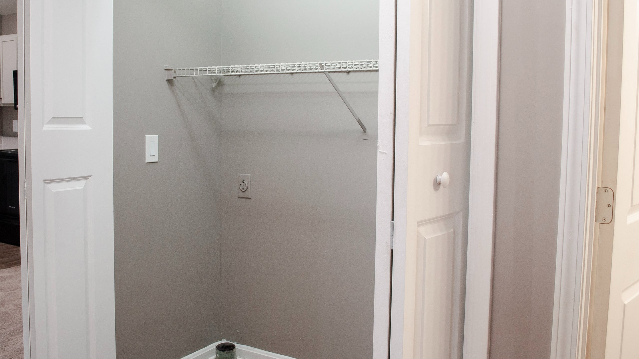 Charming apartment walk-in closet with sleek shelving, modern paint, and seamless access to a tidy kitchen area.
